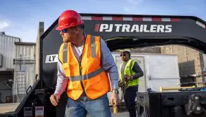 Workers loading equipment onto the Low-Pro With Hydraulic Dove Trailer