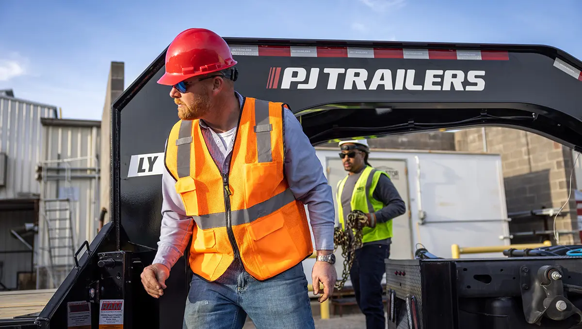 Workers loading equipment onto the Low-Pro With Hydraulic Dove Trailer