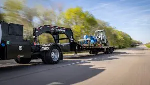 Truck with a Low-Pro With Hydraulic Dove Trailer carrying a heavy-duty forklift