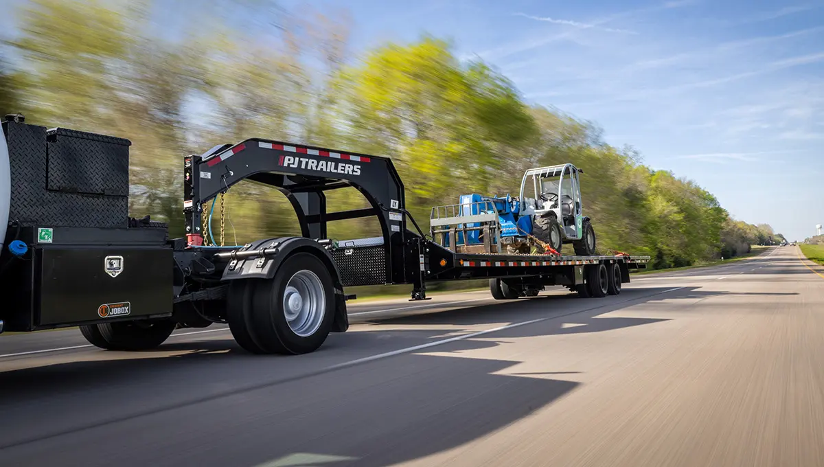 Truck with a Low-Pro With Hydraulic Dove Trailer carrying a heavy-duty forklift